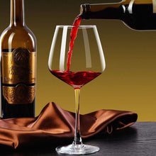 Red wine glass with burgundy wine, clear goblet on base beside bottle and cloth