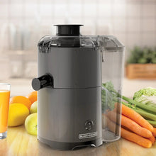 Fruit and vegetable juicer with transparent pulp container, black base, and side spout