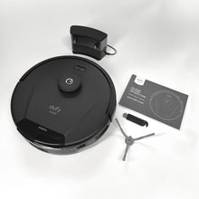 Robot vacuum cleaner with accessories and manual packaging laid out on white.
