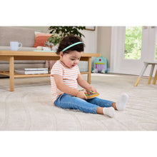 Baby kneeling on carpet using an orange learning tablet toy with colorful icons