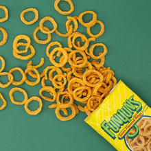 Crunchy ring-shaped chips from yellow bag on green surface
