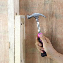 Black and pink hammer tool gripping a nail on a wooden board
