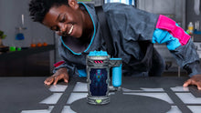 Blue lab mutation chamber container on play mat beside a person reaching toward it