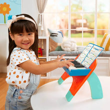Toddler playing a mini musician's piano with open songbook
