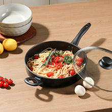 Black non-stick cooker pan with spaghetti and cherry tomatoes on wooden table