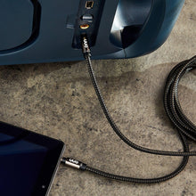 3.5 mm AUX cable with braided black jacket and gold-plated connector plugged into device