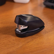 Black Swingline manual stapler on wooden desk surface