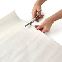 Wrapping paper sheet being cut with scissors by hands