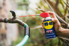 WD-40 Multi-Use spray can with red straw nozzle misting a metal pipe connection