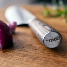 Stainless Damascus knife with dark wood handle, blade tip near red onion on board