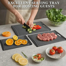 Dark grey plastic cutting boards used to slice and serve vegetables and meat.