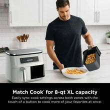 Air fryer on counter with basket removed; fries being scooped into a bowl