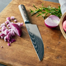 Stainless chef knife with Damascus pattern blade and dark wood handle on wooden board