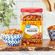 Honey roasted peanuts jar with red lid and label, with bowls of peanuts nearby