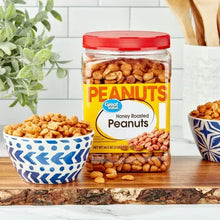 Honey roasted peanuts jar with orange lid next to two bowls of peanuts