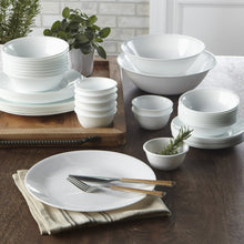 White glass salad plate on tray with forks and stacked bowls beside it