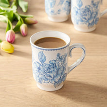 Blue floral stoneware mug filled with coffee and curved handle