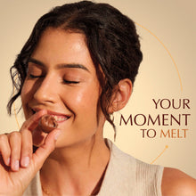 Person biting a Lindor white chocolate truffle, revealing a creamy melted center