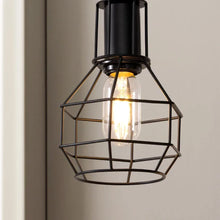 Close-up of a black metal caged floor lamp shade with exposed filament bulb
