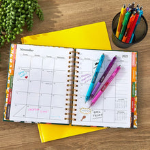 Assorted retractable gel pens with colorful barrels lying across a planner