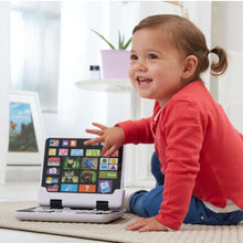 Smiling child using Infinifun 2-in-1 toy tablet while reaching at the screen