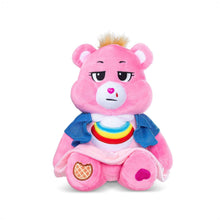 Pink plush bear sitting with blue jacket, rainbow collar, and heart snout
