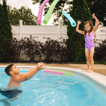 Foam pool noodles floating in backyard pool, pink and green visible