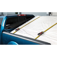 Ratchet tie-down straps securing a white cargo cover in a truck
