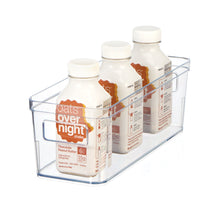 Clear plastic pantry organizer bin with built-in handles, holding bottles and cartons.