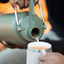 Turquoise ceramic-lined insulated water jug pouring into a cup
