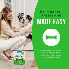 Minties dental treats pack held near dog on floor, green bone chews