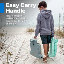 Teal kids flip seat with carry handle, folded for transport on a beach