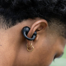 Close-up of black open-ear clip earbuds on a person’s ear with ear hook