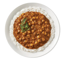 Channa masala chickpea curry over rice in a white bowl, topped with herb