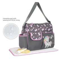 Gray unicorn-print diaper bag with included changing pad on a pink mat