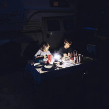 Lit LED camping lantern on a campsite table during evening meal