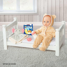 Baby doll in tan hooded sleeper sitting in a white doll bed with plush elephant.