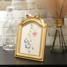 Gold resin tabletop picture frame with bow topper and floral photo insert