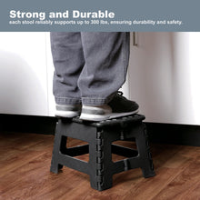 Foldable plastic step stool, black, with textured top and anti-skid feet under use