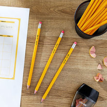 Yellow sharpened #2 wood pencils with pink erasers on a desk surface