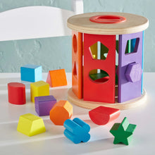 Wooden shape sorter drum with multicolor geometric pieces on a tabletop