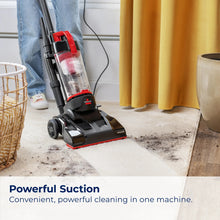 Upright vacuum on hard flooring with clear canister and red base trim.