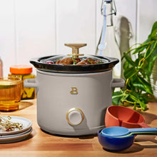 Porcini taupe manual slow cooker with black lid, food inside, gold knob