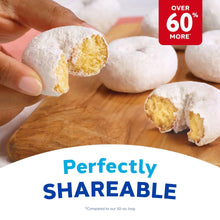 Powdered mini donut held with fingers, showing white coating and yellow filling