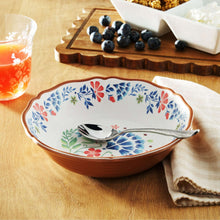 Floral serving bowl with blue and red blossoms, brown rim; black utensil inside.