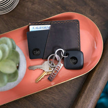 Two black Tile trackers with keys on a red tray