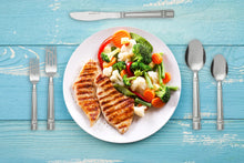 Stainless steel fork and spoon with knife beside a plate