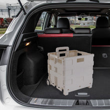 White collapsible utility cart in car cargo area with wheels and handle