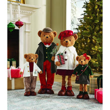 Four plush teddy bears dressed as a holiday family in coats, hats, skirts and trousers.