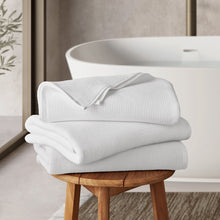 Arctic white spa towel set, stacked folded towels on a wooden stool